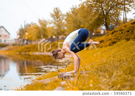 A young sports girl practices yoga on a fall A young sports girl practices yoga on a fall 59560371