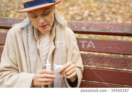Low-spirited lady staring at her nasal spray 59560387