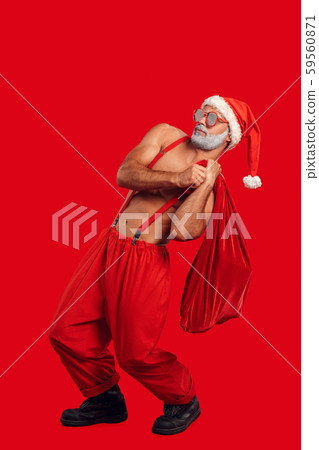Christmas Freestyle. Young bearded Santa Claus bare muscular upper body in hat and sunglasses Christmas Freestyle. Young bearded Santa Claus bare muscular upper body in hat and sunglasses 59560871