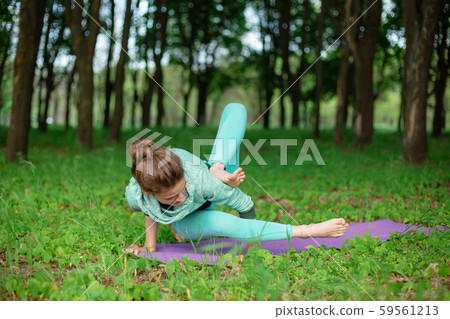 A young sports girl practices yoga in a quit green A young sports girl practices yoga in a quit green 59561213