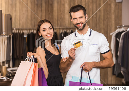 Young adult woman and man in fashionable boutique holding plastic credit card Young adult woman and man in fashionable boutique holding plastic credit card 59561406