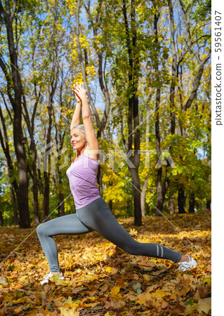 Contented flexible female yogi practicing yoga outdoors Contented flexible female yogi practicing yoga outdoors 59561407