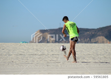 Back view of a foreign professional soccer player lifting on the beach_1 59561805