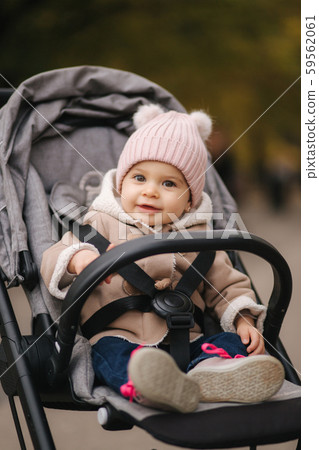 Cute little baby in pram. Adorable baby girl in autumn sitting in her pram Cute little baby in pram. Adorable baby girl in autumn sitting in her pram 59562061