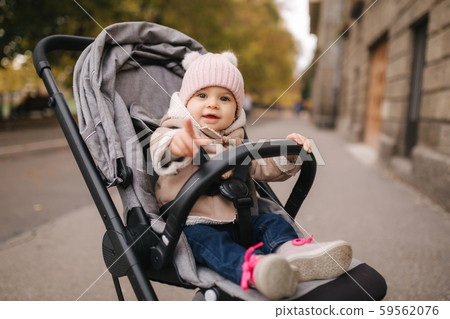 Cute little baby in pram. Adorable baby girl in autumn sitting in her pram Cute little baby in pram. Adorable baby girl in autumn sitting in her pram 59562076