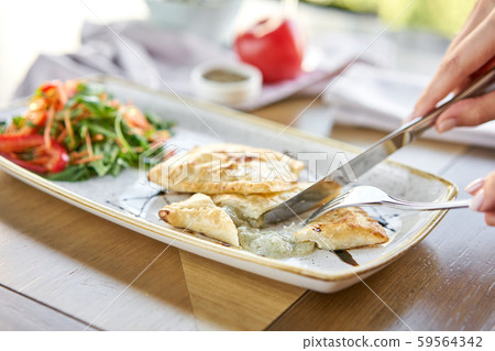 Woman eats Latin American fried empanadas with Vegetable salad with arugula. Decorated with balsamic 59564342