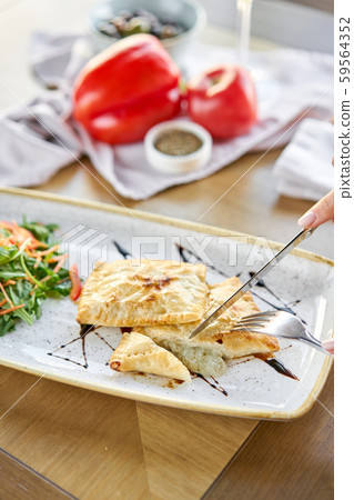 Woman eats Latin American fried empanadas with Vegetable salad with arugula. Decorated with balsamic 59564352