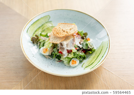 Olivier salad with Lamb tongue, salted cucumber, quail egg. Wooden table background. Menu restaurant 59564465