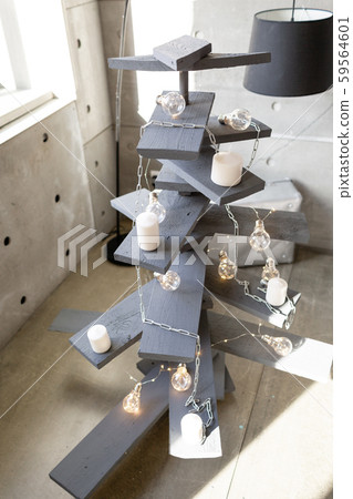 Alternative wooden christmas tree. A handmade Christmas tree and light bulb on the floor in the room Alternative wooden christmas tree. A handmade Christmas tree and light bulb on the floor in the room 59564601