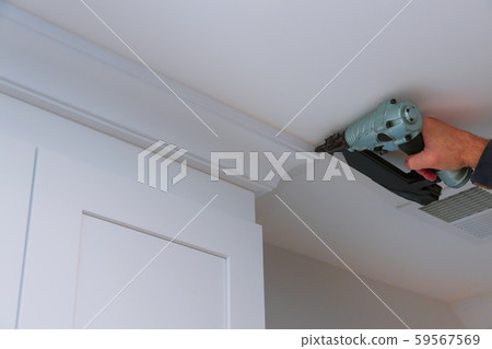 Carpenter nailing crown moldings in the kitchen Carpenter nailing crown moldings in the kitchen 59567569