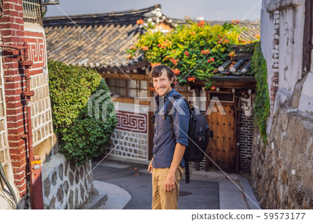 Young man tourist in Bukchon Hanok Village is one of the famous place for Korean traditional houses Young man tourist in Bukchon Hanok Village is one of the famous place for Korean traditional houses 59573177