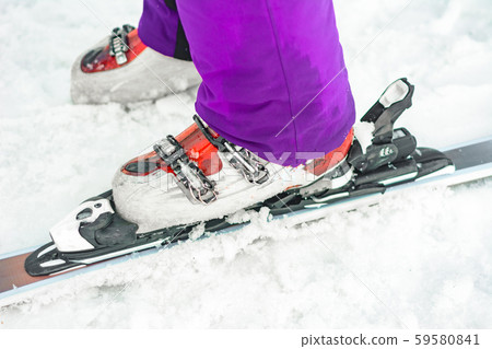 The athlete skier demonstrates a set of skis and boots on the leg. The athlete skier demonstrates a set of skis and boots on the leg. 59580841