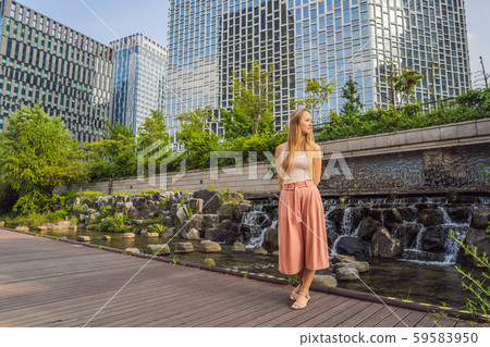 Young woman tourist in Cheonggyecheon stream in Seoul, Korea. Cheonggyecheon stream is the result of Young woman tourist in Cheonggyecheon stream in Seoul, Korea. Cheonggyecheon stream is the result of 59583950