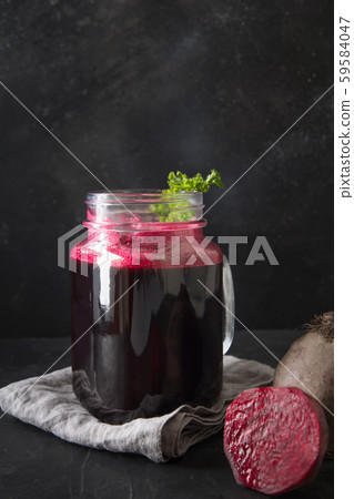 Glass of fresh beetroot juice garnish parsley on black. Vertical orientation. 59584047