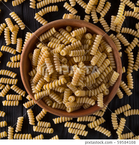 Top view of fusilli pasta in bowl and scattered on black wooden table Top view of fusilli pasta in bowl and scattered on black wooden table 59584108