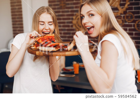 Cute friends in a cafe eatting a pizza Cute friends in a cafe eatting a pizza 59584562