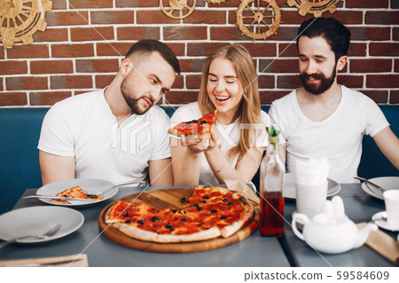 Cute friends in a cafe eatting a pizza Cute friends in a cafe eatting a pizza 59584609