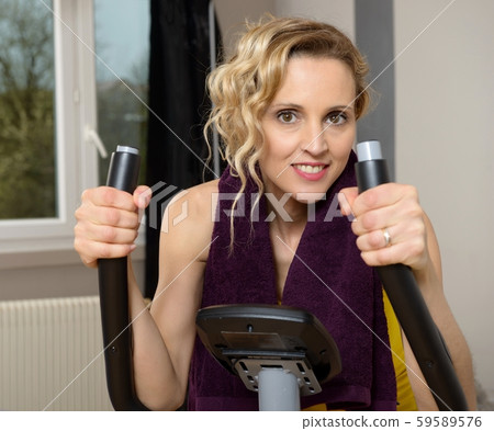 Fit woman on exercise bike  at home 59589576