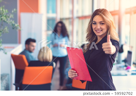 Business woman with folders standing and team mates working in meeting room at office.