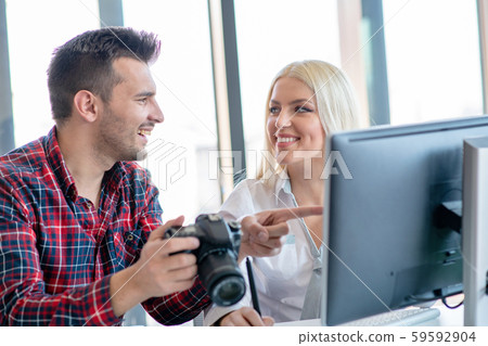 Graphic designer wearing casual clothes talking with colleague while using graphics tablet at the 59592904