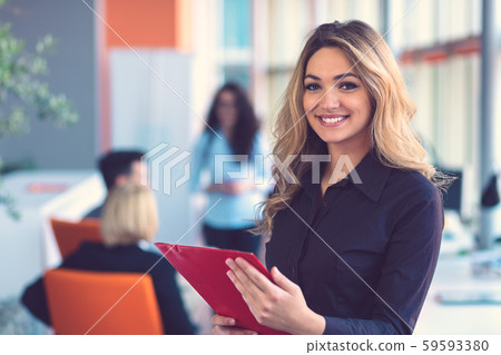 Business woman with folders standing and team mates working in meeting room at office.