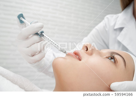 Young client receiving procedure botox of lips. 59594166