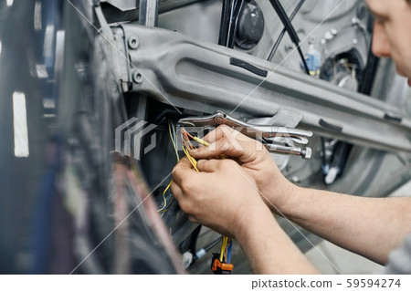 Close up of mechanics bare hands fixing electricity in car 59594274