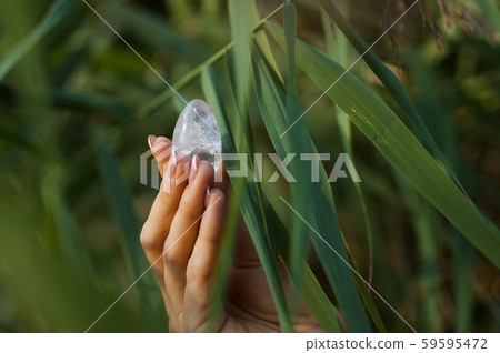 Female hand with french manicure holding transparent violet amethyst yoni egg for vumfit, imbuilding Female hand with french manicure holding transparent violet amethyst yoni egg for vumfit, imbuilding 59595472