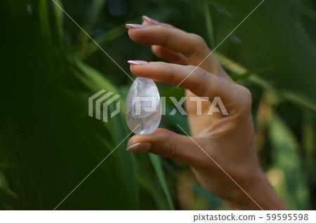 Female hand with french manicure holding transparent violet amethyst yoni egg for vumfit, imbuilding 59595598