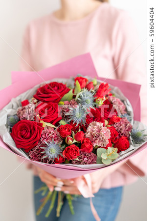 Mixed bouquet of red tones. Beautiful bunch of fresh flowers in womans hands. The work of the Mixed bouquet of red tones. Beautiful bunch of fresh flowers in womans hands. The work of the 59604404
