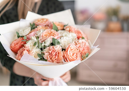 Beautiful bouquet of mixed flowers in womans hands. the work of the florist at a flower shop Beautiful bouquet of mixed flowers in womans hands. the work of the florist at a flower shop 59604530