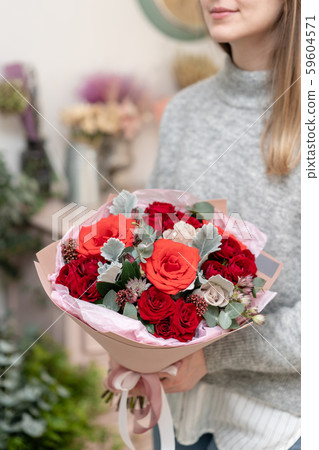 Mixed bouquet of red tones. Beautiful bunch of fresh flowers in womans hands. The work of the Mixed bouquet of red tones. Beautiful bunch of fresh flowers in womans hands. The work of the 59604571