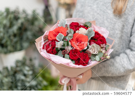 Mixed bouquet of red tones. Beautiful bunch of fresh flowers in womans hands. The work of the Mixed bouquet of red tones. Beautiful bunch of fresh flowers in womans hands. The work of the 59604577