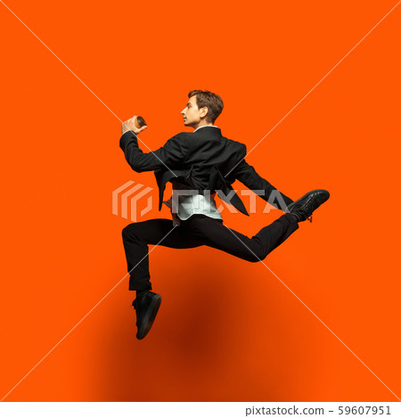 Man in casual office style clothes jumping isolated on studio background Man in casual office style clothes jumping isolated on studio background 59607951