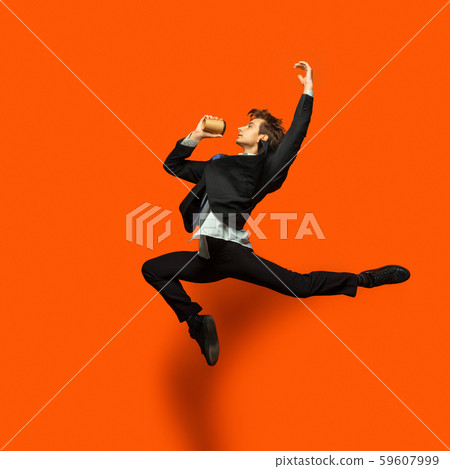 Man in casual office style clothes jumping isolated on studio background Man in casual office style clothes jumping isolated on studio background 59607999