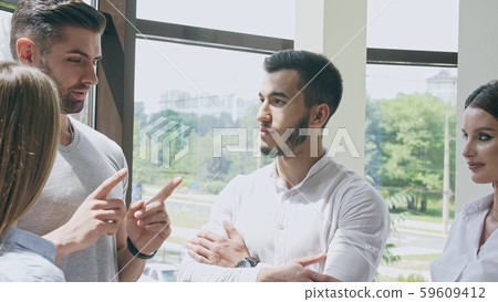 Small company of two men and two women in an office in a small talk with each other Small company of two men and two women in an office in a small talk with each other 59609412