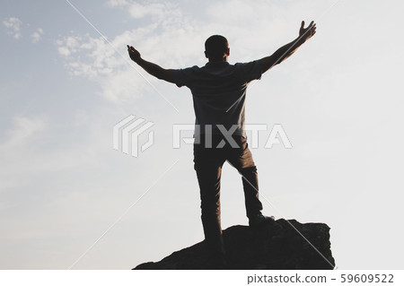 Man silhouette hands up on the rock Man silhouette hands up on the rock 59609522