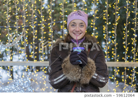 Beautiful woman in winter clothes with coffee in hand On the background of beautiful bokeh. outdoor. 59612064