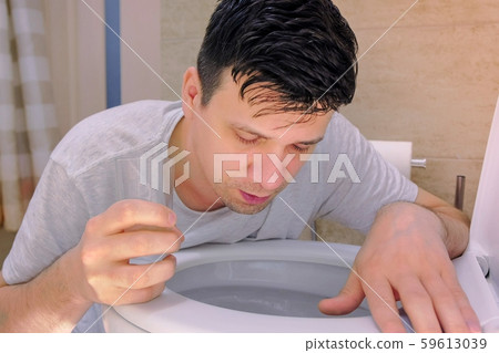 Portrait of man is vomiting in toilet and drinking water feeling bad having flu. Portrait of man is vomiting in toilet and drinking water feeling bad having flu. 59613039