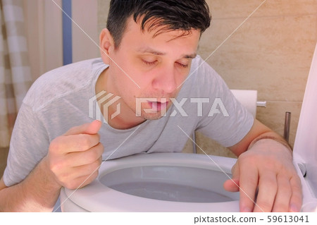Portrait man vomiting in toilet after food poisoning with two fingers in mouth. Portrait man vomiting in toilet after food poisoning with two fingers in mouth. 59613041