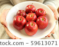 Seven princess apples on a white plate that a woman holds with both hands 59613071