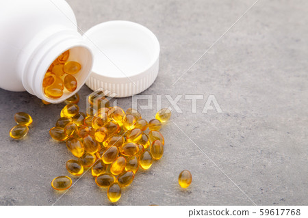 Top view of scattered from pill bottle Gold fish oil for good health on gray background. Food 59617768