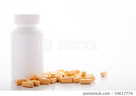 Closeup scattered from white pill bottle orange oval medicine vitamins for pregnancy, pills, drugs 59617774