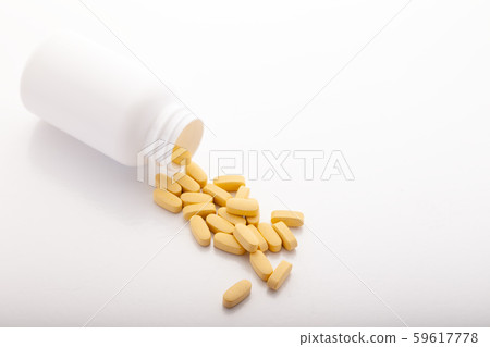 Closeup scattered from white pill bottle orange oval medicine vitamins for pregnancy, pills, drugs 59617778