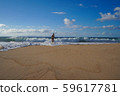 A young woman in a swimsuit is running from a wave 59617781