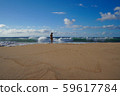 A young woman in a swimsuit is standing on an empty sandy beach 59617784