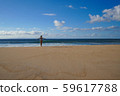 A young woman in a swimsuit is standing on an empty sandy beach 59617788