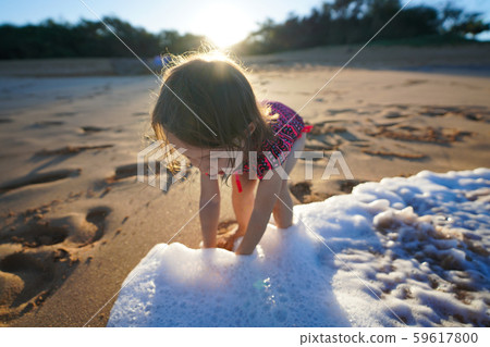Toddler girl playing with water on the beach 59617800