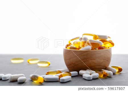 Assortment scattered pharmaceutical medicine tablets, pills, drugs in wooden bowl on gray background 59617807