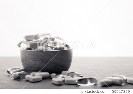 Many scattered medicine vitamins, pills, drugs in bowl on gray background. White food dietary 59617809